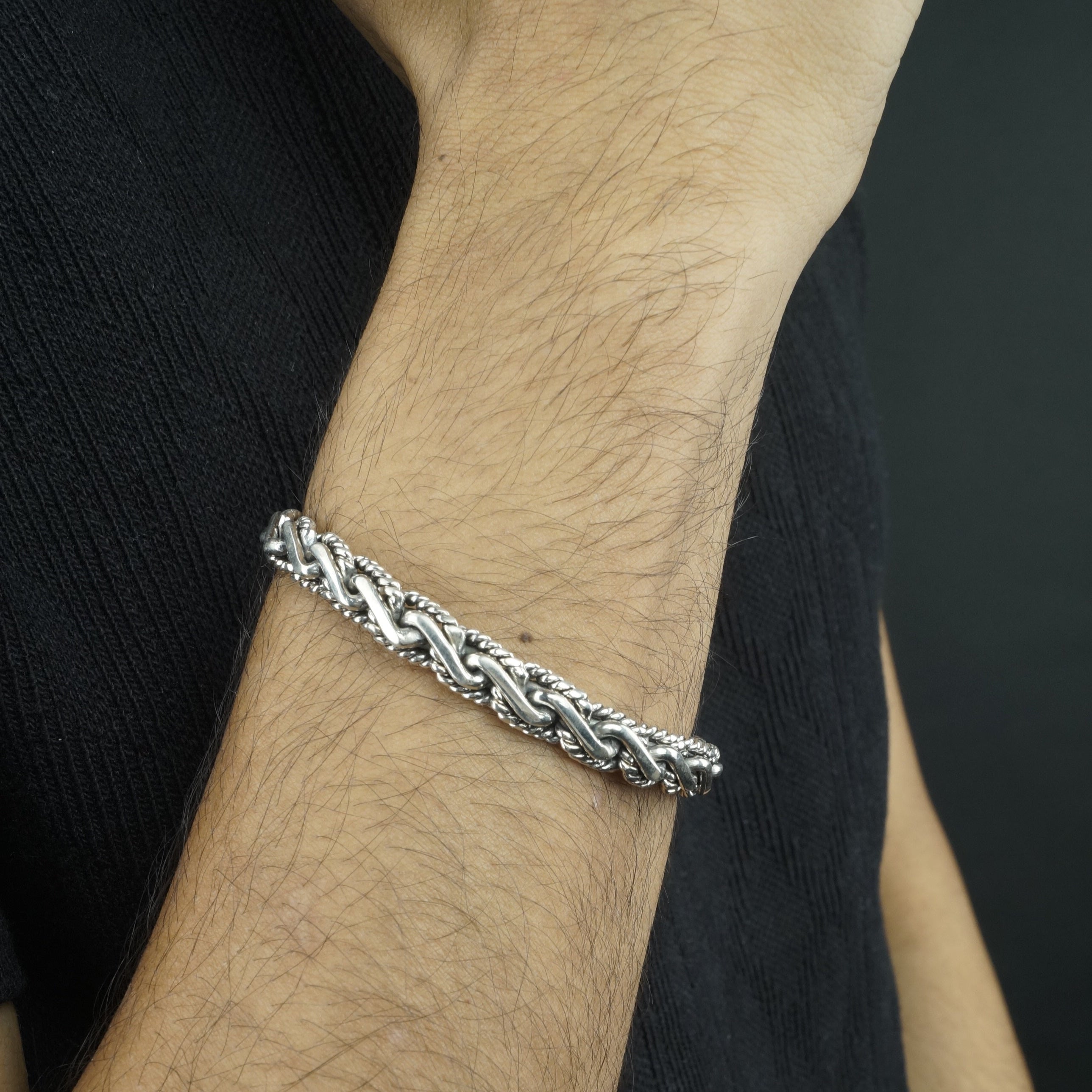 Silver bracelet on a person's wrist with a dark background