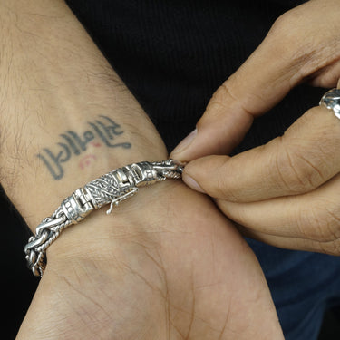 Close-up of a hand wearing a silver bracelet with a dark background